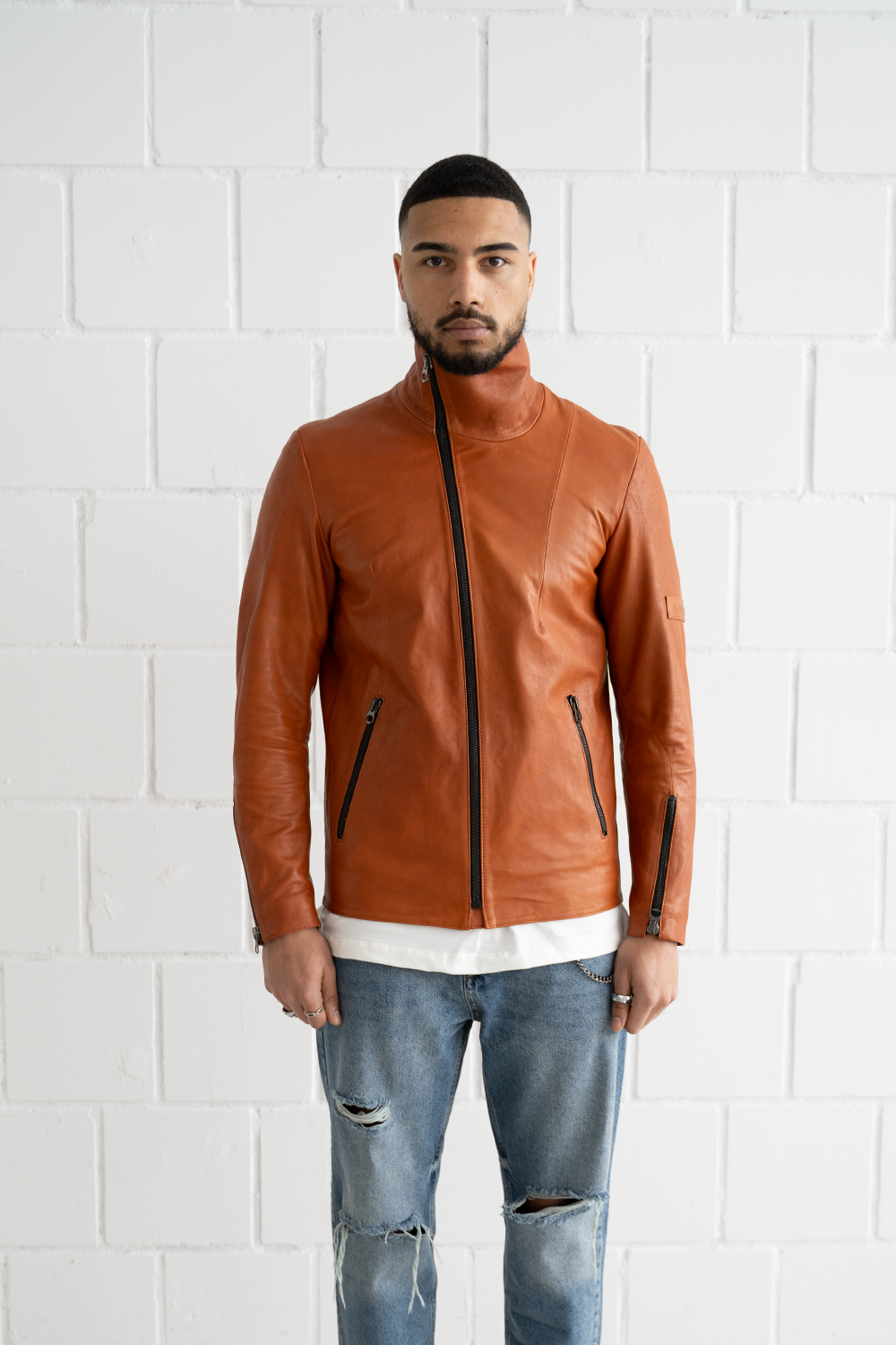 Front view of the Vaarora asymmetrical camel leather jacket highlighting the distinctive diagonal zipper and slim fit, worn closed