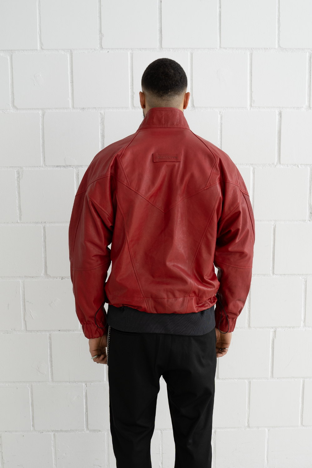 Back view of a male model wearing the oversized Vaarora Vittorio leather jacket in red highlighting the V-shaped seams