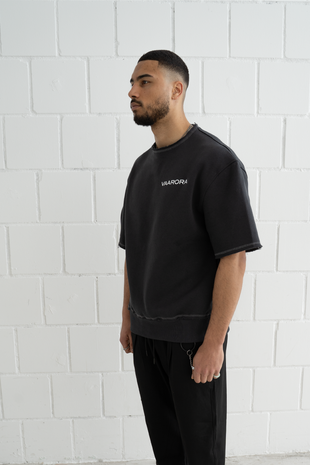 Side profile of a male model in the oversized Vaarora Cato Heavy Tee highlighting the raw-edge sleeves and premium mid-weight fabric