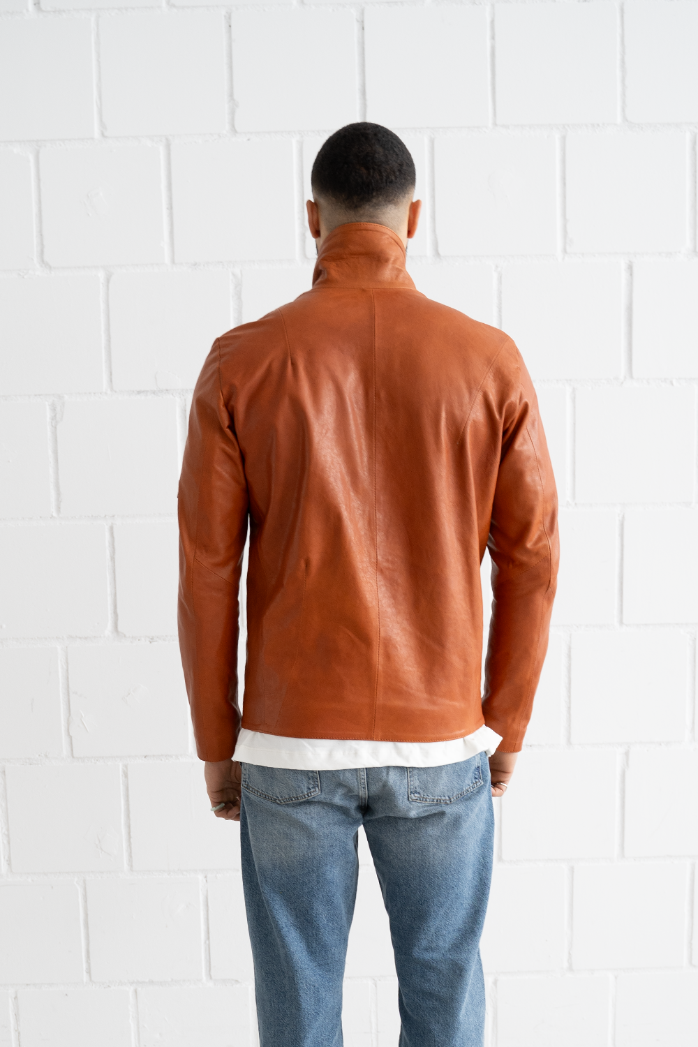 Back view of a male model wearing the Vaarora asymmetrical premium leather jacket in camel