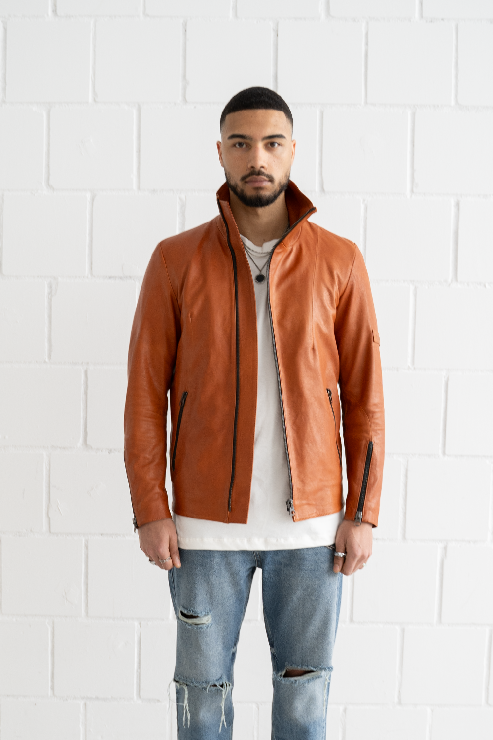 Front view of a male model wearing the Vaarora asymmetrical leather jacket in camel, worn open